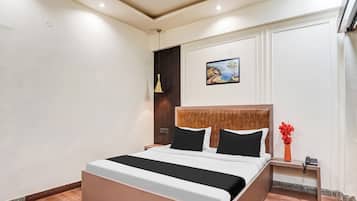 Ein modernes Hotelzimmer mit einem großen Bett, einem Gemälde an der Wand und einem Nachttisch mit einem Telefon.