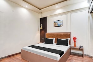 A modern hotel room with a large bed, a painting on the wall, and a bedside table with a phone. - OYO Collection O Ratan Lal Nagar (Kanpur)