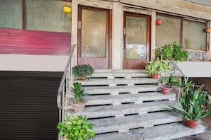 A set of outdoor steps leading to a building entrance with multiple potted plants. - OYO Collection O Ratan Lal Nagar (Kanpur)