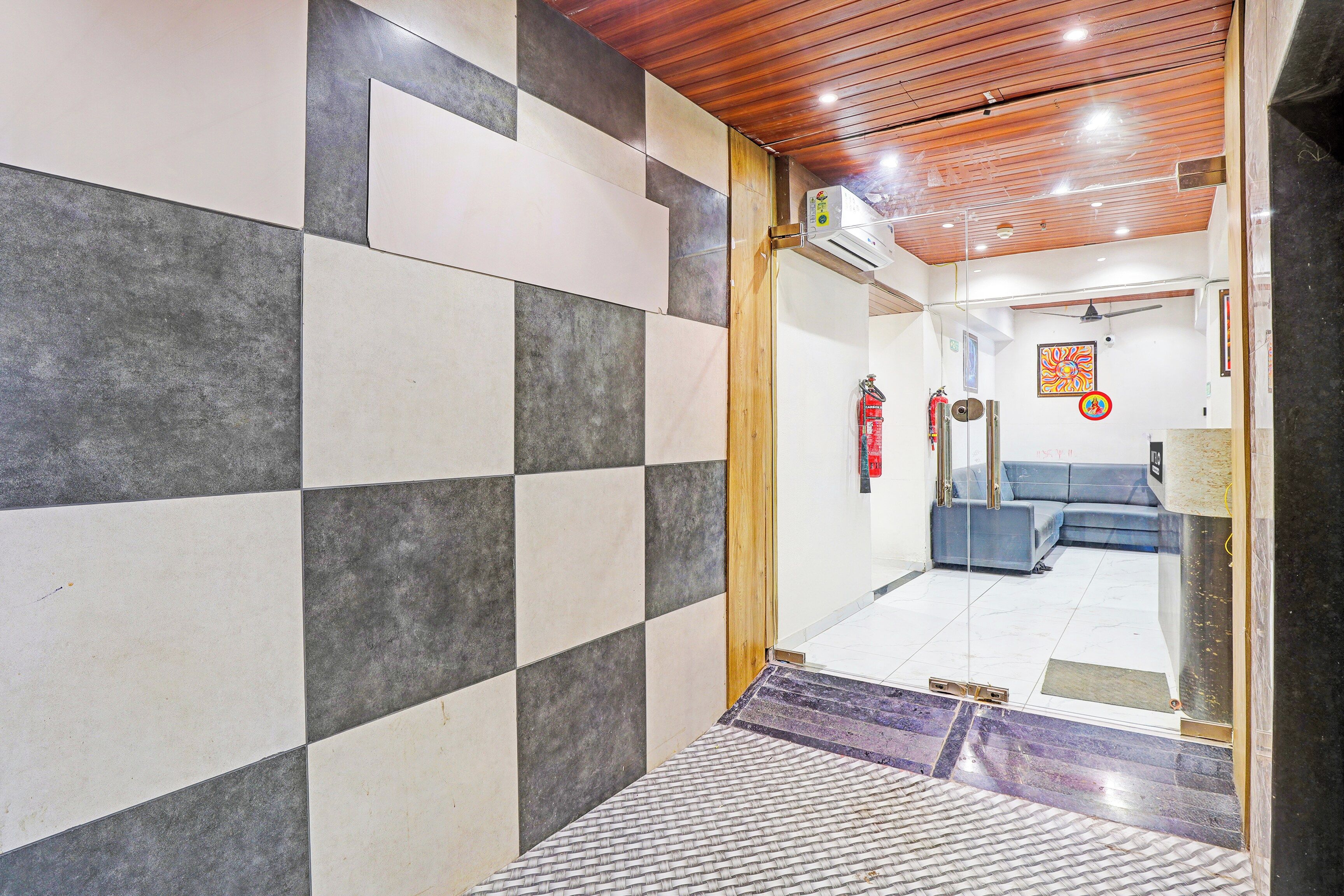 A hallway with checkered tile walls, a wooden ceiling, and a blue sofa in the background.