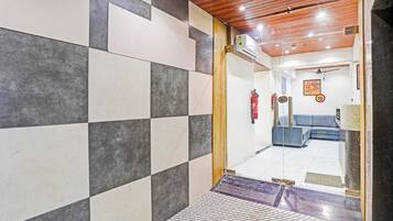A hallway with checkered tile walls, a wooden ceiling, and a blue sofa in the background.
