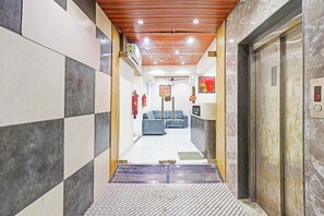 A hotel lobby with a check-in counter, a reception desk, and a seating area. - Hotel O Althan Formerly Hotel Niraant (Surat)