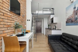 A compact living space with a dining area, kitchenette, and a loft bedroom. - Cracow | Lubelska 5 | Functional Studio | Close to the Old Town (Kraków)