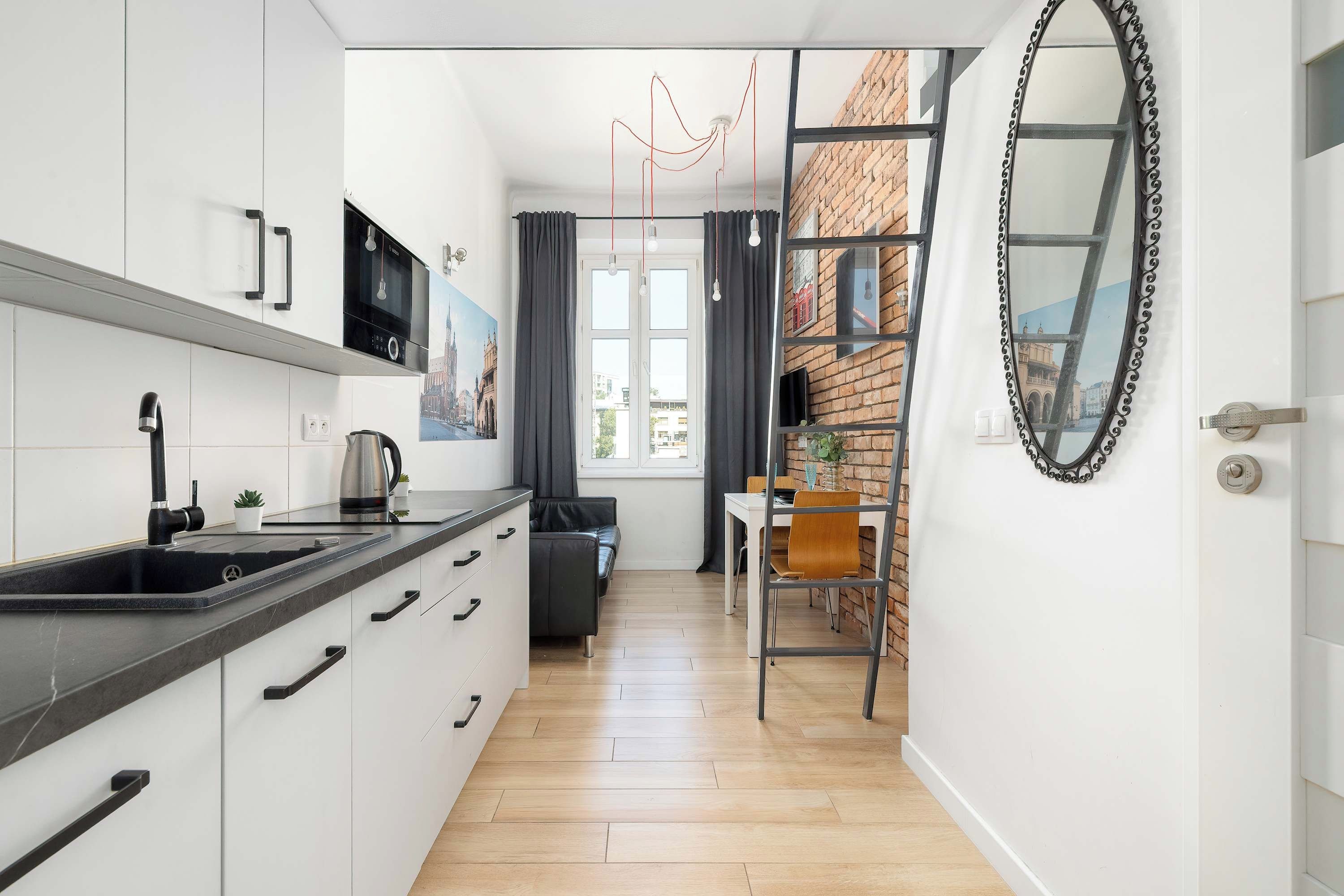 A modern kitchen with a black sink, white cabinets, and a Bosch microwave.