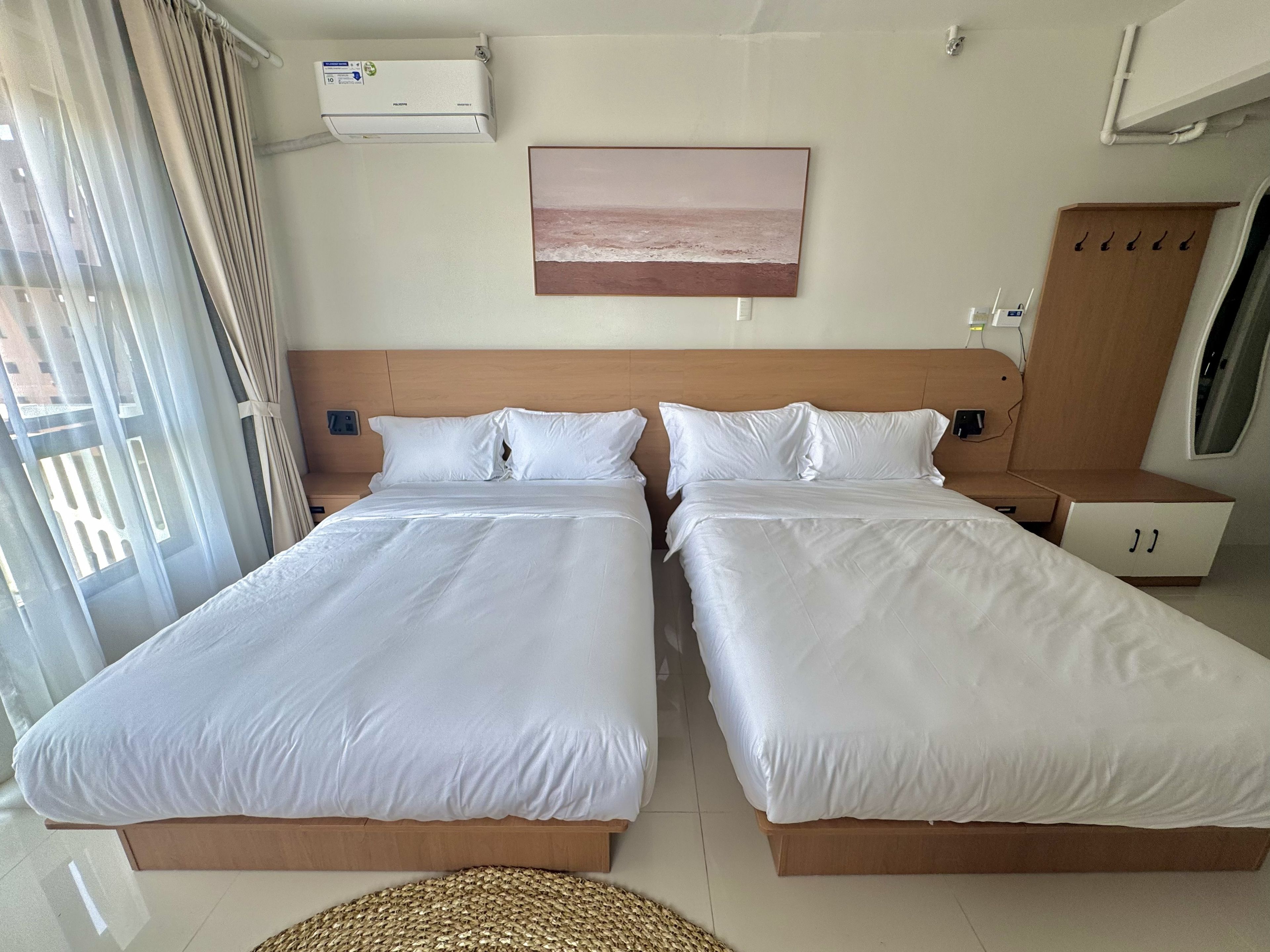 Une chambre d’hôtel avec deux lits, un tableau, un climatiseur et une armoire.