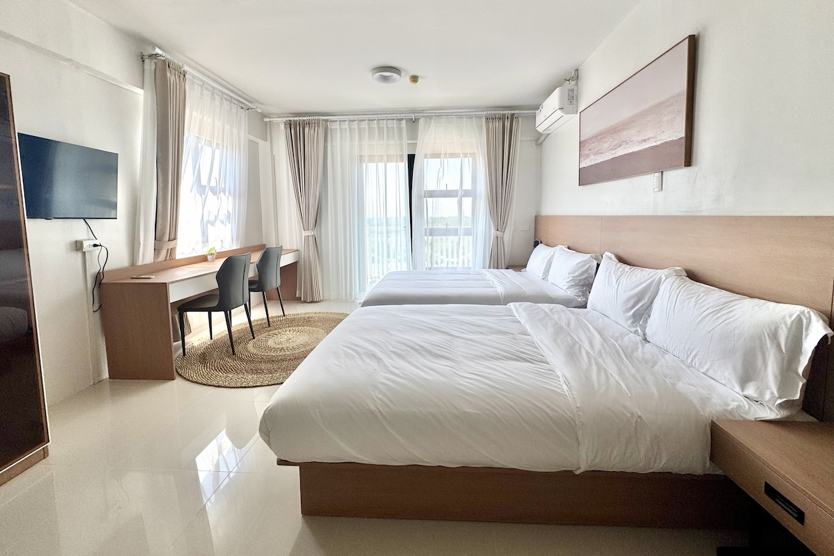 Una habitación de hotel con una cama grande, un escritorio con silla, un televisor y una ventana con cortinas.