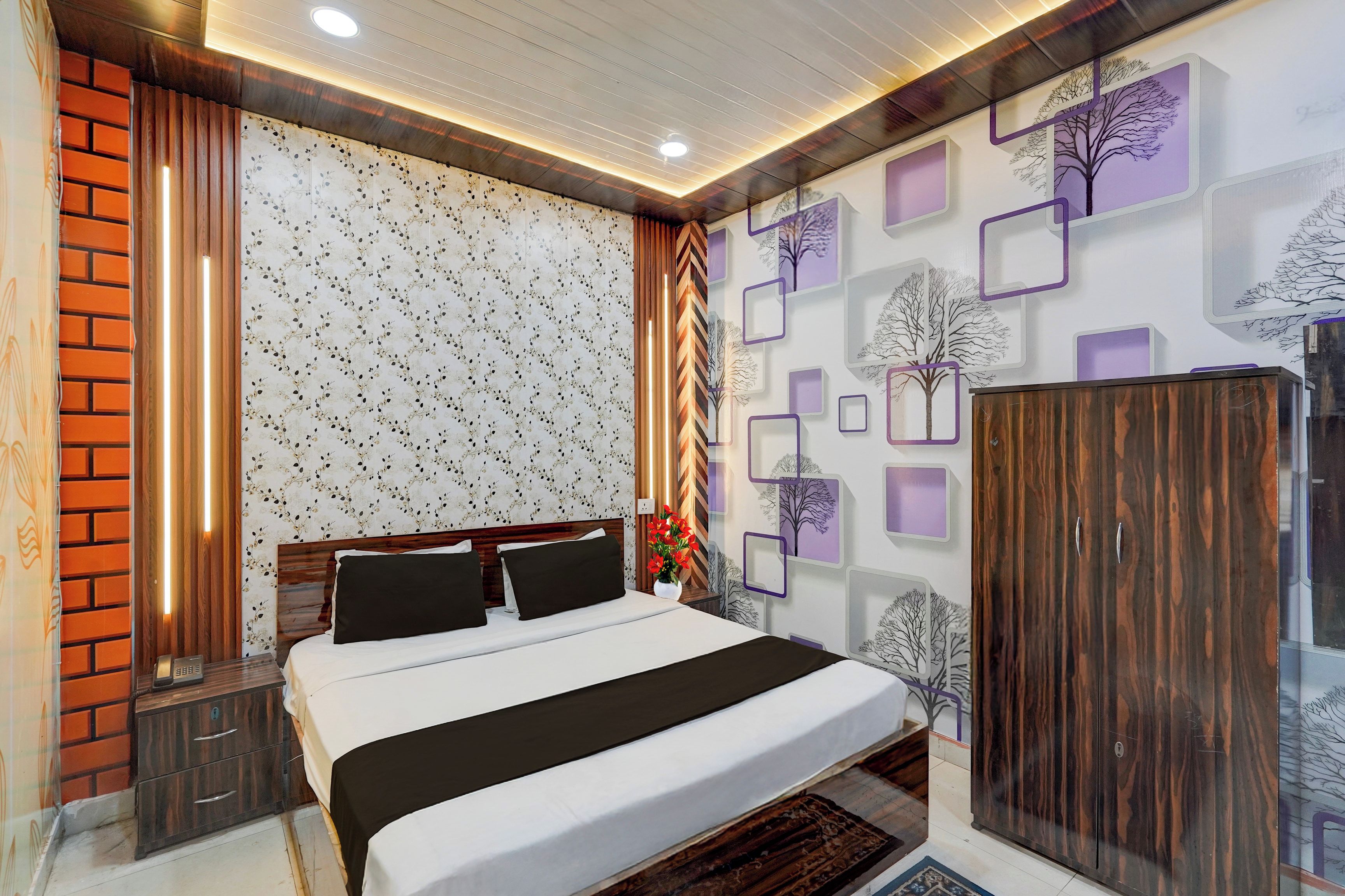 Una camera d'albergo con un letto, un armadio, un comodino e una parete decorata con motivi floreali.