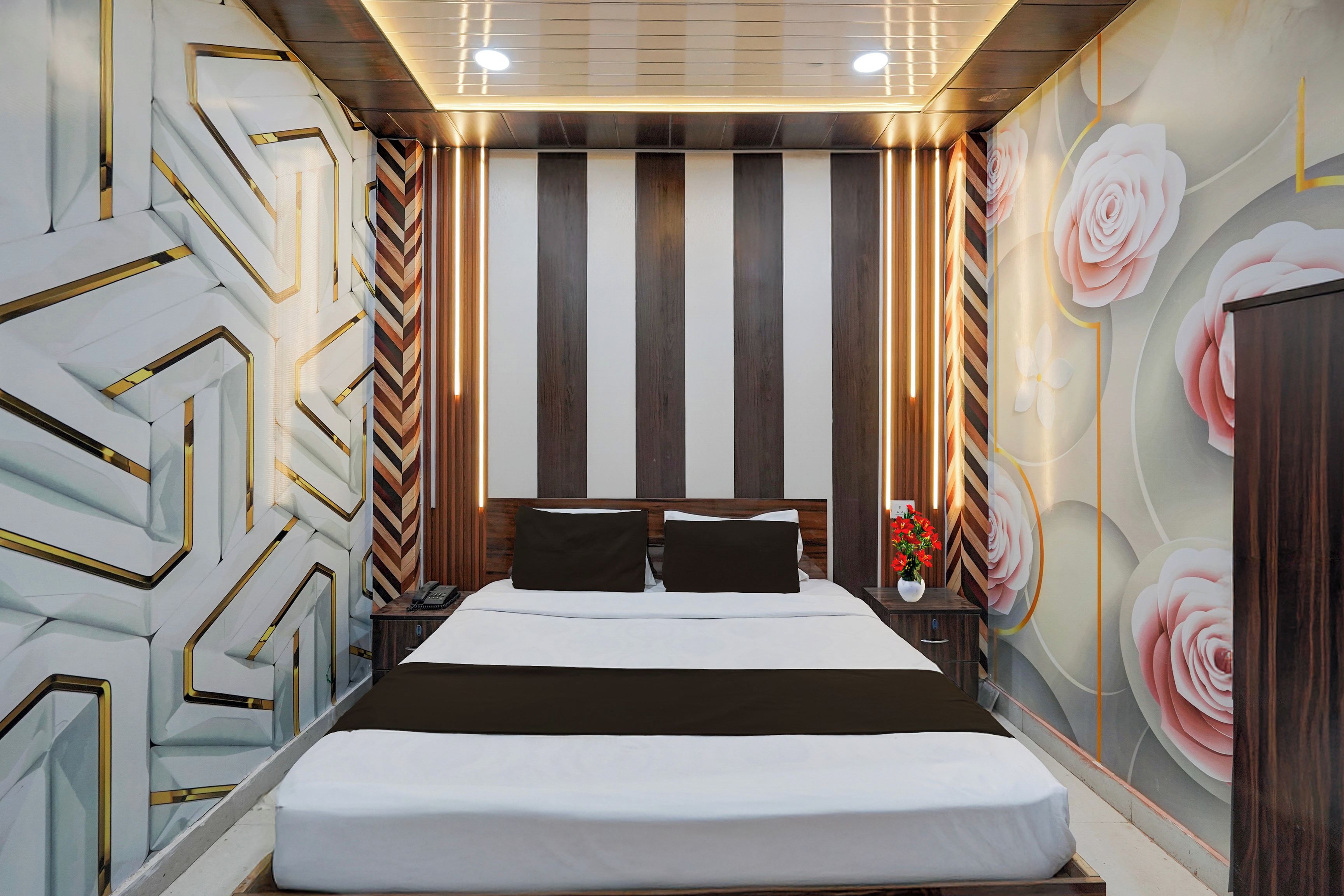 Una camera d'albergo moderna con un letto grande, una testiera in legno e una parete con motivo a righe.