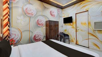 A hotel room with a bed, a TV mounted on the wall, and a decorative wall with floral patterns.