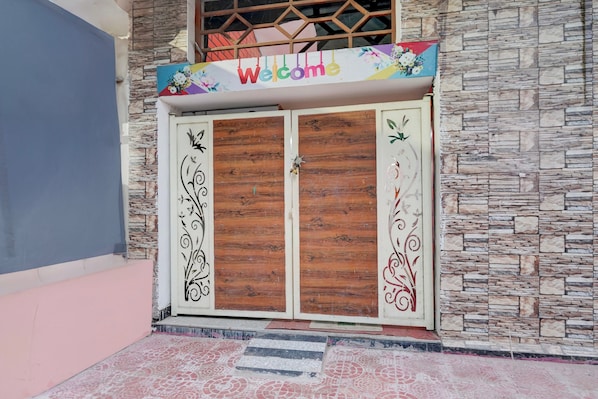 A double wooden door with decorative metalwork and a 'Welcome' sign above it.