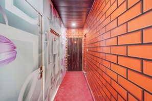 A corridor with a red carpet, a wooden door, and a brick wall.