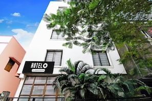 Un hotel con letrero, varias ventanas y abundante vegetación.