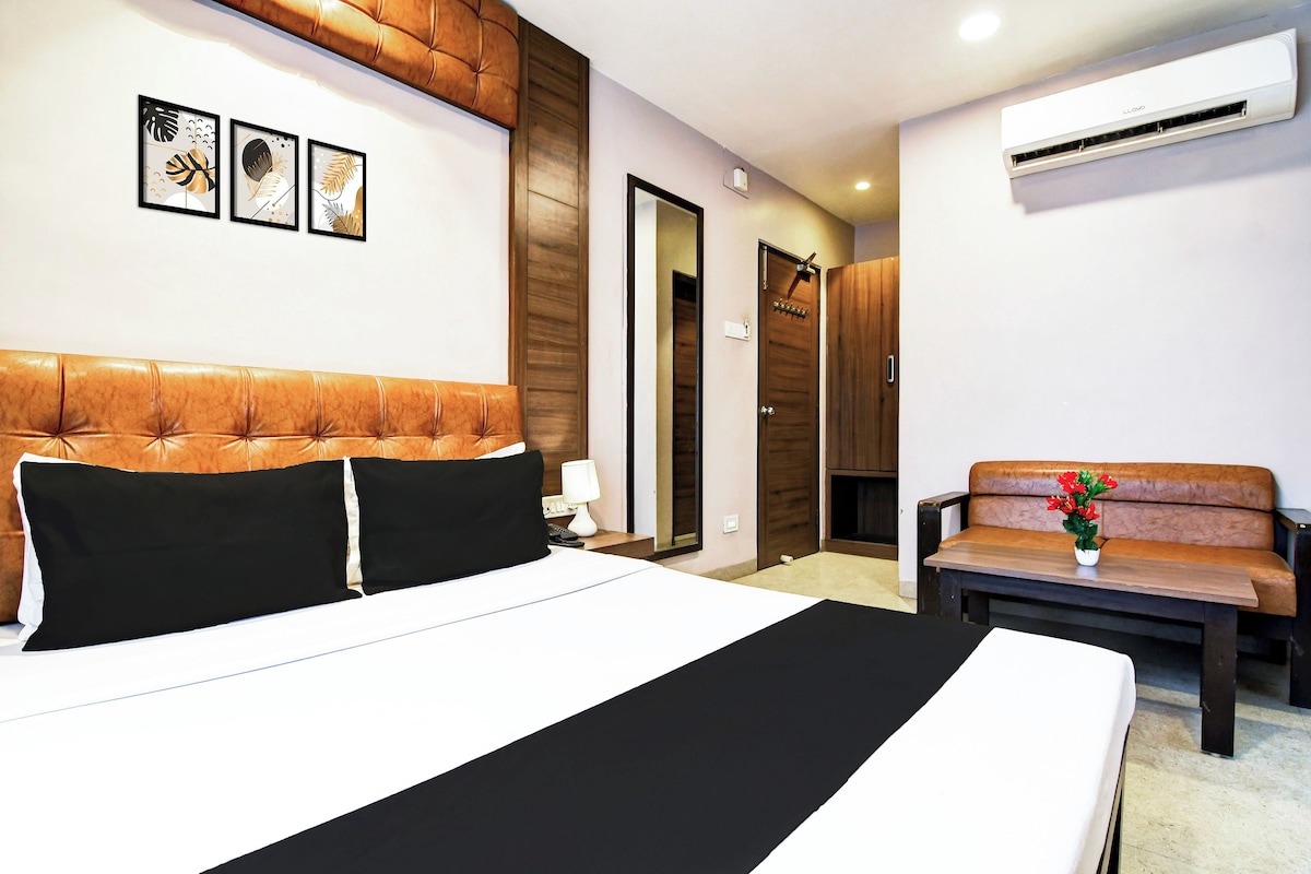 Habitación de hotel con una cama grande, un sofá, un escritorio y aire acondicionado de pared.