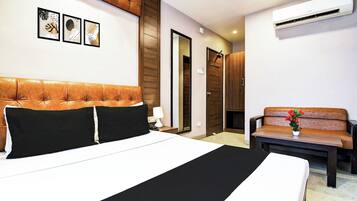 Habitación de hotel con una cama grande, un sofá, un escritorio y aire acondicionado de pared.