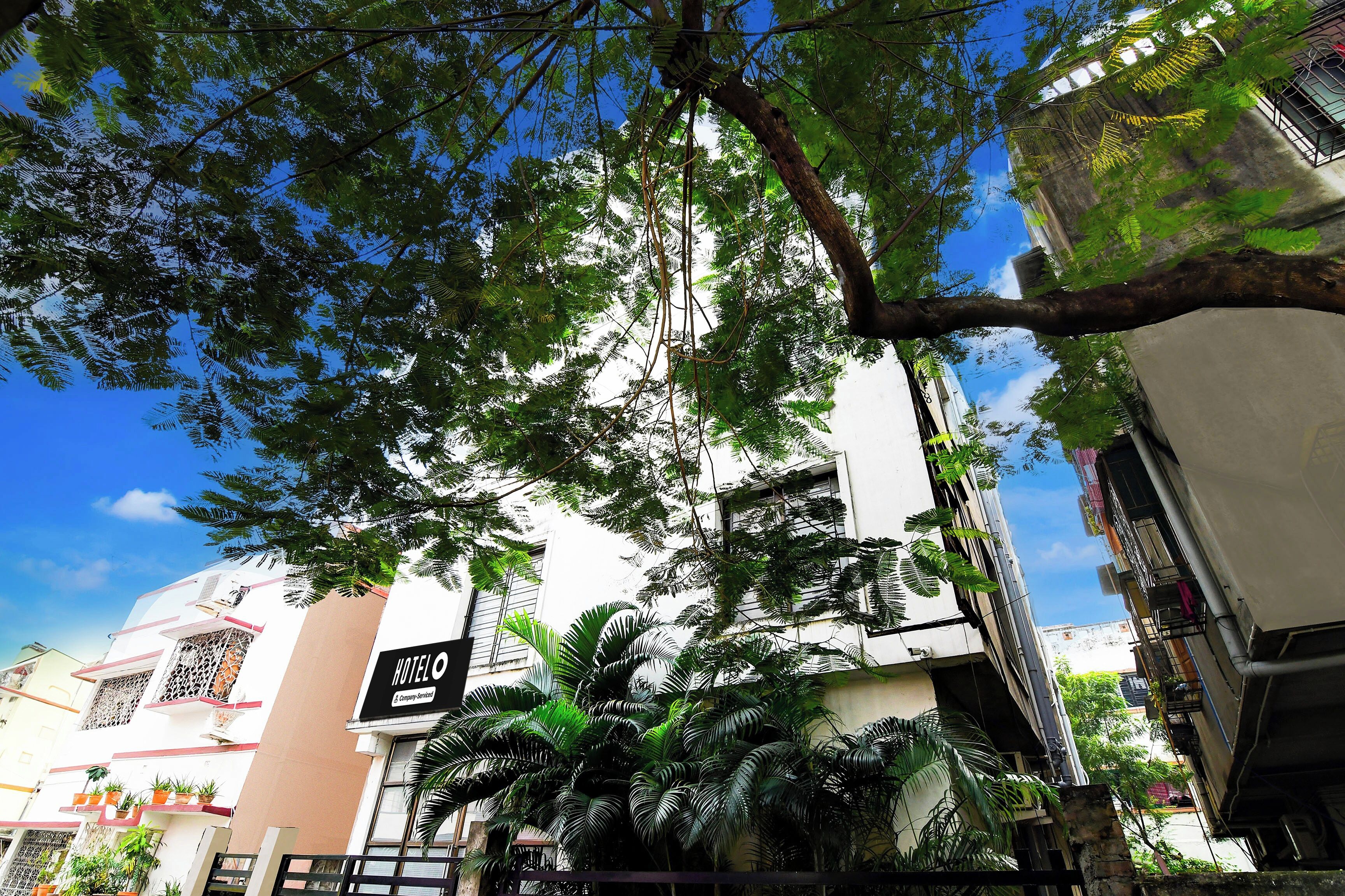Un hotel con un letrero que indica servicio empresarial, rodeado de vegetación exuberante y un cielo azul despejado.