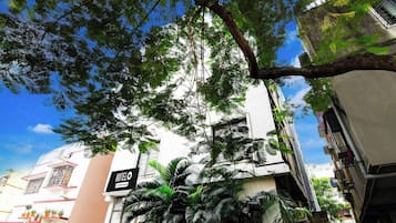 Un hotel con un letrero que indica servicio empresarial, rodeado de vegetación exuberante y un cielo azul despejado.