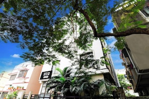 Un hotel con un letrero que indica servicio empresarial, rodeado de vegetación exuberante y un cielo azul despejado.