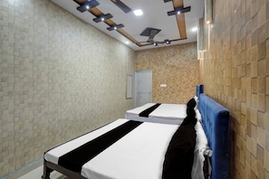 Quarto de hotel com duas camas, um ventilador de teto e um guarda-roupa.