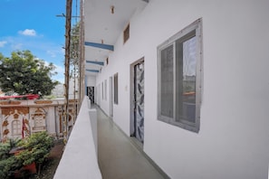 Um corredor com paredes brancas, chão de azulejos e várias portas e janelas.