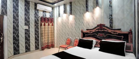A hotel room with a large bed, a decorative headboard, and a patterned wall.