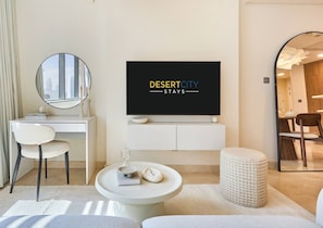 A modern hotel room with a flat-screen TV, a desk, a chair, a round table, and a mirror. - Chic & Stylish Unit|Prime Location Near Dubai Mall (Dubai)