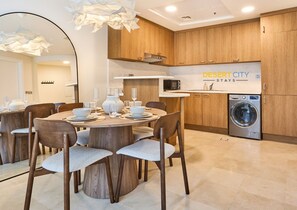 A modern kitchen with wooden cabinets, a microwave, and a washing machine. - Chic & Stylish Unit|Prime Location Near Dubai Mall (Dubai)