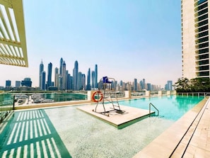 Ein Pool auf dem Dach mit Blick auf die Stadtlandschaft, einem Rettungsschwimmerstand und einem Sprungbrett.