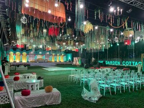 An outdoor event space with a stage, chairs, and tables arranged for an event.