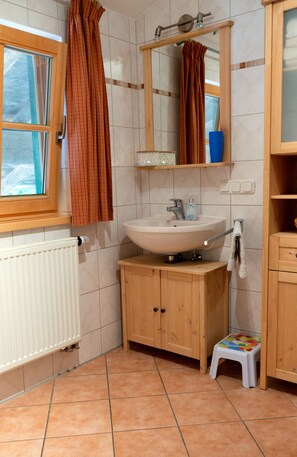 Ein Badezimmer mit Holzschrank, Waschbecken, Spiegel und Fenster.