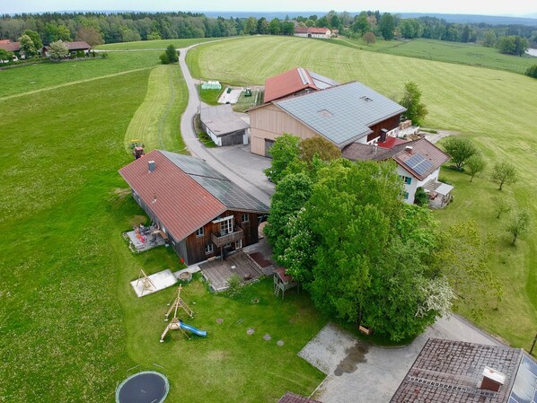 Ein ländliches Anwesen mit einer großen Scheune, einem Haus mit Solaranlage und einem Spielplatz.