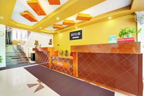 A hotel reception area with a reception desk, a staircase, and a sign indicating 'HOTEL' and 'BOOKING & SERVICE'.