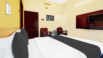 A hotel room with a large bed, a television mounted on the wall, and a desk with two chairs.