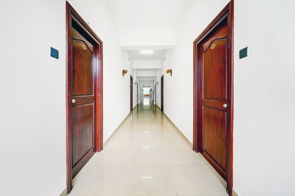 A long, narrow hallway with wooden doors on either side and a tiled floor.