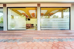 A building entrance with a glass door, a tiled floor, and a staircase leading up.