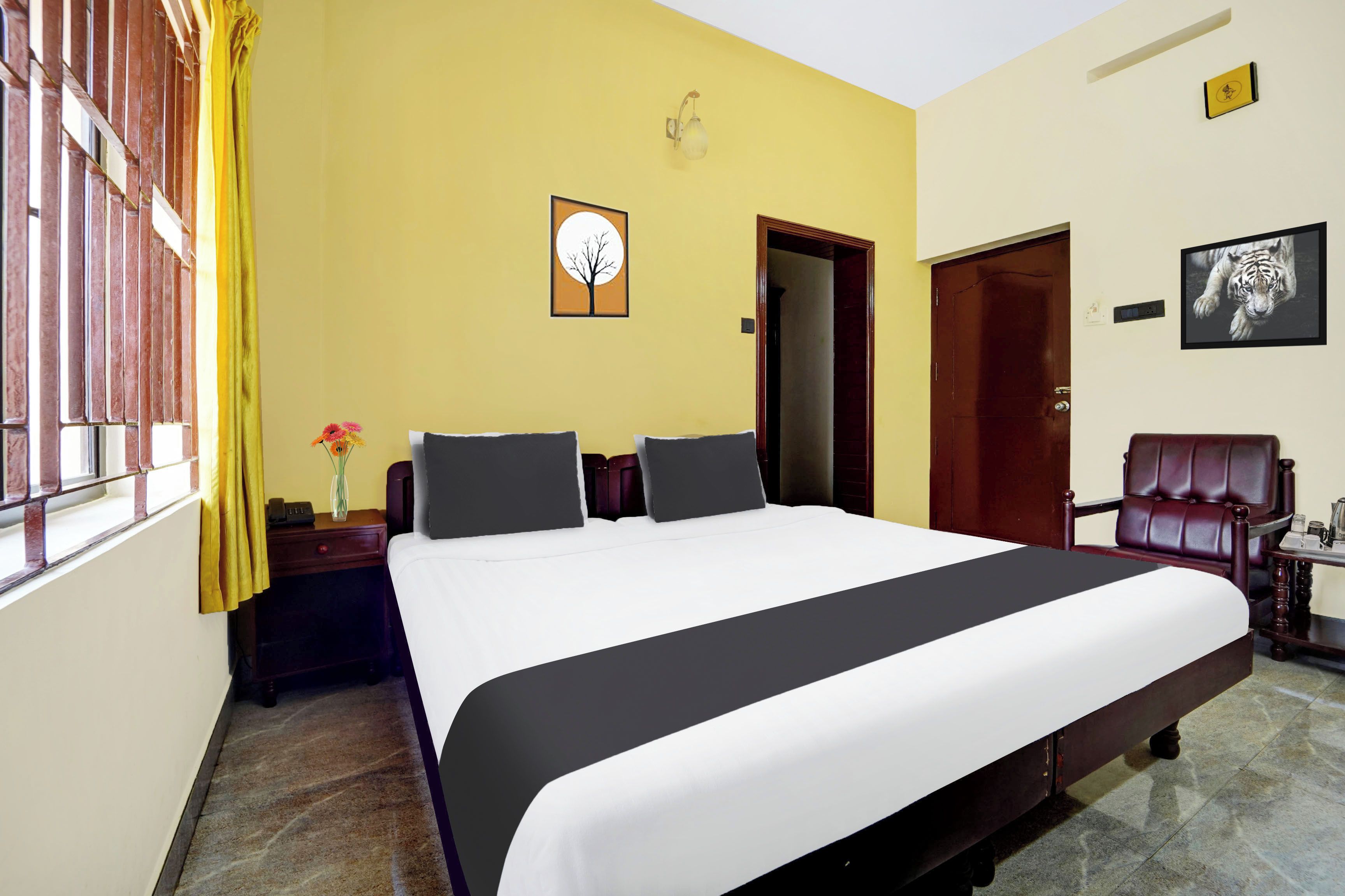 A hotel room with a large bed, a nightstand, a chair, and a wall-mounted TV.