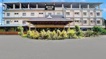 Hotel com entrada coberta, vários andares e aparelhos de ar condicionado.