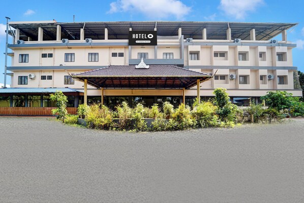 A hotel with a covered entrance, multiple floors, and air conditioning units.
