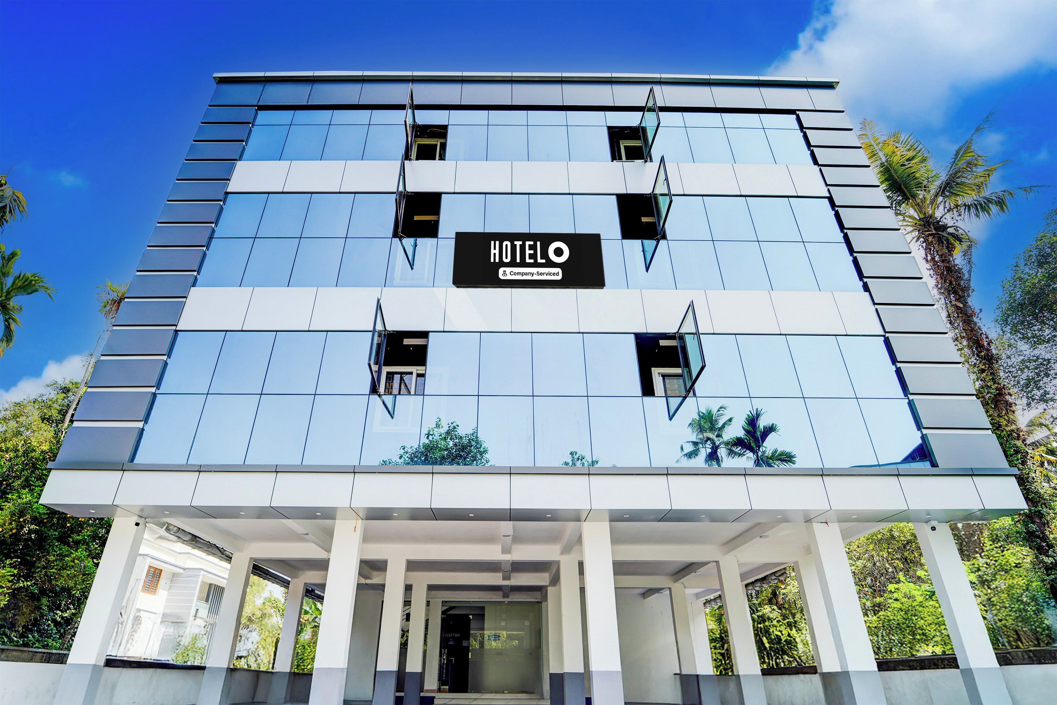 A modern hotel building with a sign indicating it is a company-serviced establishment.