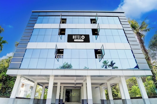 A modern hotel building with a sign indicating it is a company-serviced establishment.