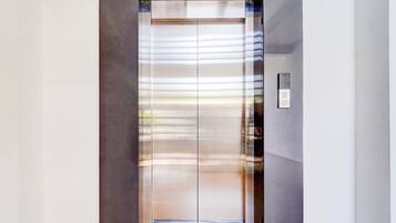 Un ascensor moderno con detalles metálicos y un panel de control a la derecha.