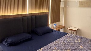 A hotel room with a bed, a nightstand, a lamp, and a window with blinds. - Room-charming B&B Room With Private Faci (Jammu)