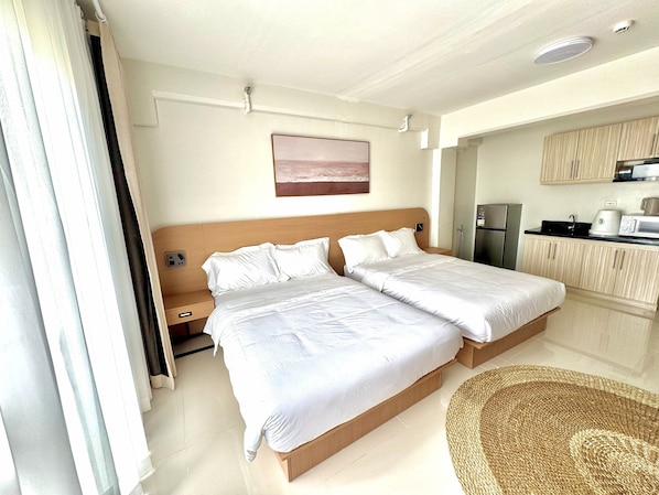 A hotel room with a double bed, a small kitchenette, and a bathroom. - Royal Oceancrest Panglao 1 (Dauis)