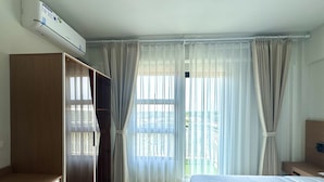 A hotel room with a bed, a wardrobe, an air conditioning unit, and a window with curtains. - Royal Oceancrest Panglao 1 (Dauis)
