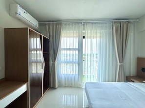 Ein Hotelzimmer mit einem Bett, einem Kleiderschrank, einer Klimaanlage und einem fensterbepflanzten Fenster.