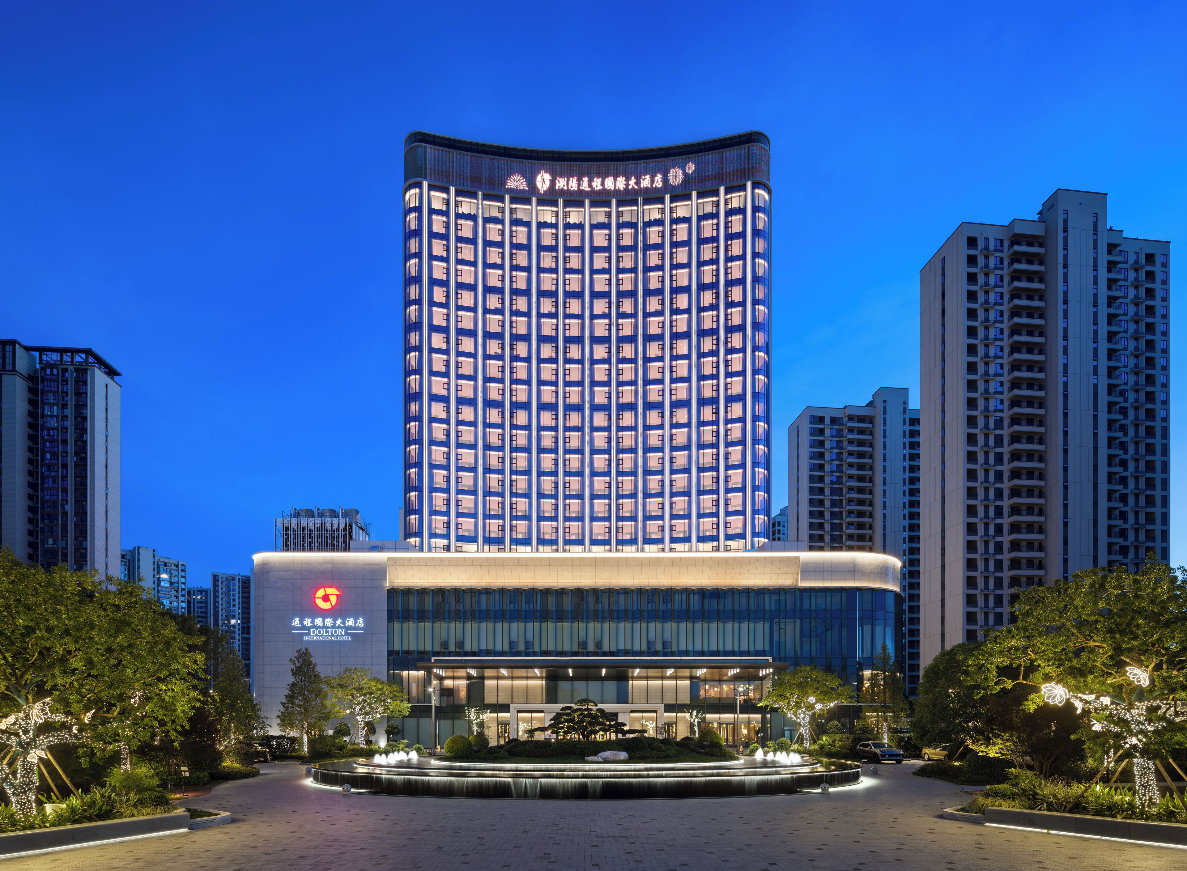 A modern hotel with a curved facade, multiple floors, and a central courtyard with a water feature.