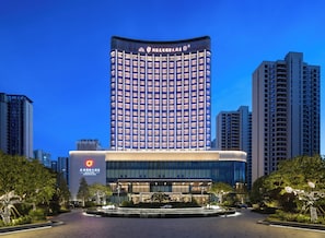 A modern hotel with a curved facade, multiple floors, and a central courtyard with a water feature. - LIUYANG DOLTON INTERNATIONAL HOTEL (Changsha)
