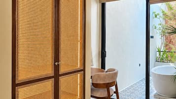Una habitación con puerta corredera, una silla, un tazón blanco grande y vistas a un jardín.