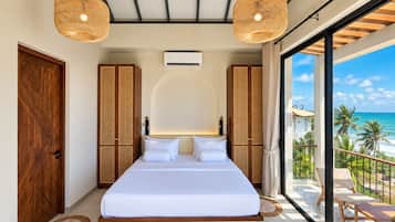 A spacious bedroom with a large bed, two wardrobes, and a balcony with a view of the ocean.