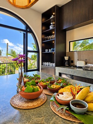 Una cocina moderna con un ventanal grande, un comedor con diversos platos, y vistas al exterior.