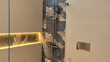 Une salle de bain moderne avec une douche à parois de verre, un mur en marbre et des toilettes.